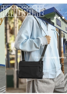 Detail of black nylon crossbody bag with multi-zipper compartments and adjustable strap