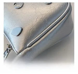 Detail of silver metallic wrinkled leather bag with metal rivets and chunky chain strap