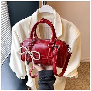 Detail of red glossy pillow bag with pearl bow pendant and silver metal hardware