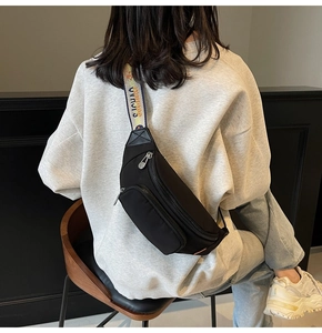 Detail of black nylon chest bag showing multi-zipper pockets and colorful SUNSHINE strap