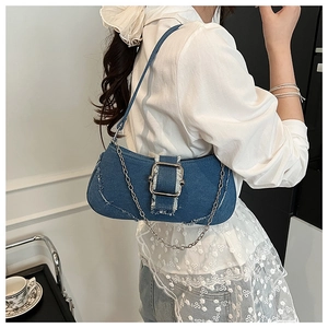 Detail of denim blue underarm bag featuring silver buckle and frayed edge design