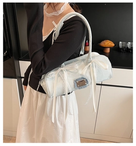 Detail einer hellblauen Stofftasche mit weißen Spitzen-Schleifen und Metallschnalle