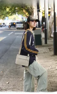 Detail of a lightweight beige nylon crossbody bag with adjustable strap and zip pockets