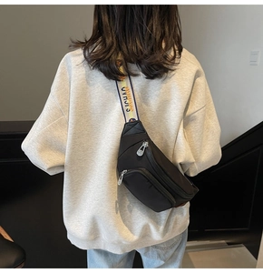 Rear view of model wearing a black fashion fanny pack with a colorful woven strap.