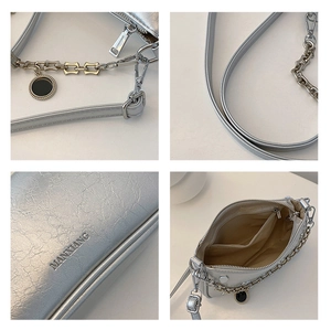 Detail view of silver pleated shoulder bag featuring metal chain and inner compartments