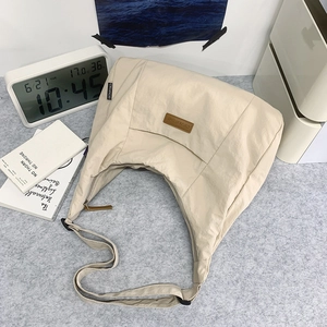 Draufsicht einer beige Canvas-Tasche mit braunem Logo-Patch auf minimalistischem Tisch