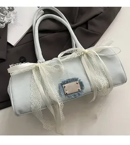 Detail der hellblauen Denim-Boston-Tasche mit großen weißen Spitzenschleifen und Plakette