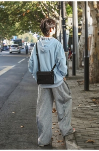Outdoor street shot of a model wearing a lightweight black nylon crossbody shoulder bag