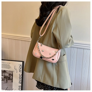 Pink Y2K shoulder bag with silver studs and metal chains shown on a green blazer