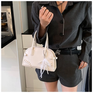 Vue détaillée du sac Boston crème avec breloque perle en dentelle et design de corset