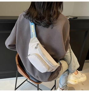 Detail of off-white nylon chest bag featuring a sporty blue and yellow lettered strap