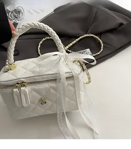 Detail of white quilted crossbody bag featuring a golden camellia and lace bow accent