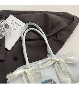 Nahaufnahme der hellblauen Denim-Tasche mit weißen Spitzenschleifen und Metallemblem