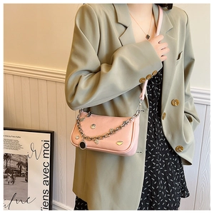 Detail of pink lychee leather crescent bag with silver metal chain and heart charm