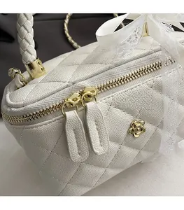Close-up of white quilted leather bag showing smooth gold zippers and camellia charm
