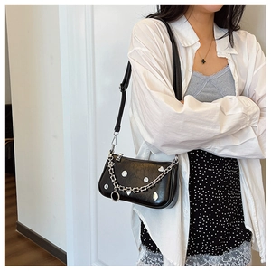 Chic black crescent bag with silver chain and heart studs shown on a shoulder