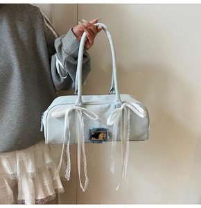 Detailansicht der Jeans-Boston-Tasche mit weißen Spitzenschleifen und Metallschnalle