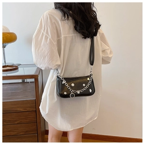 Elegante borsa a mezzaluna nera con rivetti argentati e tracolla a catena indossata