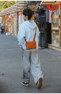 Close-up of bright orange nylon crossbody bag with multi-layer zipper pockets for daily use