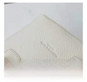 Detail der elfenbeinfarbenen Beuteltasche aus Leder mit Logo und feiner Nahtverarbeitung