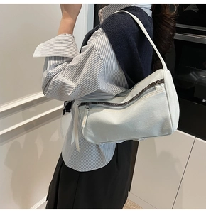 Close-up of a light canvas underarm bag featuring LIUU logo webbing and zipper pocket