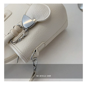 Detail der cremeweißen Eimertasche aus Litschi-Leder mit herzförmiger Metallschnalle