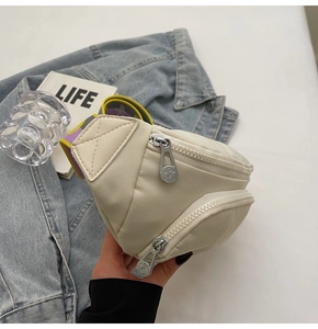 Detail view of cream nylon waist bag with metal zippers and colorful woven strap