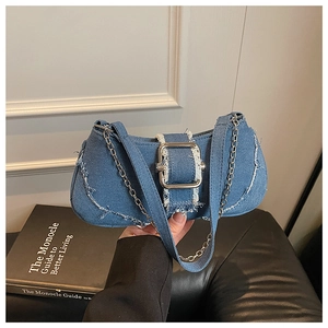 Detailed shot of blue denim shoulder bag featuring a large silver buckle and metal chain