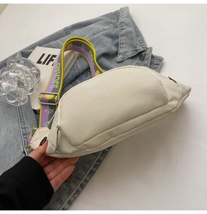 Detail of a creamy white nylon chest bag featuring a colorful wide jacquard shoulder strap