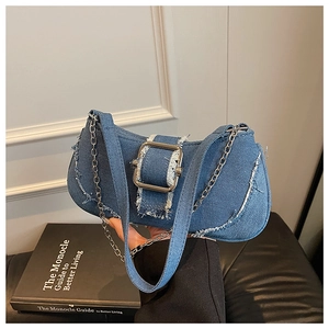 Detail of blue denim baguette bag featuring silver metal buckle and frayed edge texture