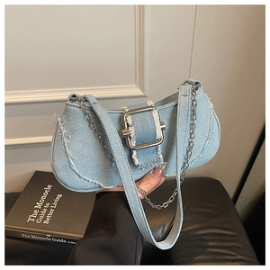 Close-up of light blue denim shoulder bag featuring distressed edges and metal buckle details