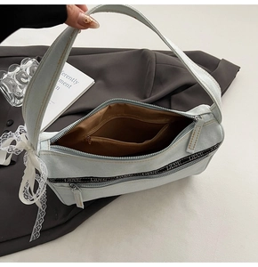 Detail view of denim baguette bag showing interior lining and lace bow decoration
