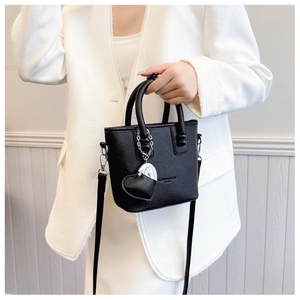 Detail der schwarzen Bucket Bag mit Litschi-Struktur, Griffen und Herzanhänger