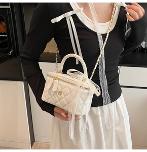 Detail of white quilted leather vanity bag with lace ribbon and golden flower accent