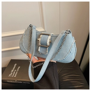 Detail view of denim shoulder bag with silver metal buckle and frayed edge texture