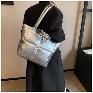 Gros plan sur le sac fourre-tout matelassé argenté avec bandoulière large et texture brillante