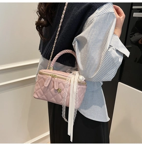 Detail of pink quilted box bag with floral zipper charms and lace ribbon accent
