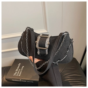 Close-up of black denim shoulder bag featuring raw edges and a large silver metal buckle
