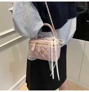 Close-up of pink quilted crossbody bag with gold flower hardware and lace bow detail