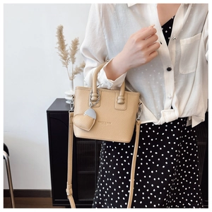 Schicke aprikosenfarbene Mini-Eimertasche mit Herzanhänger am Modell in Minimal-Optik