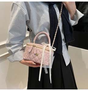 Pink quilted mini box bag with lace bow detail and chain strap worn by model