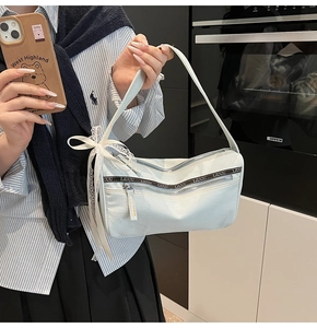 Detail of light blue denim shoulder bag with lace bows and double zipper pockets