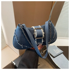Detail of blue denim shoulder bag with frayed edges and silver square metal buckle