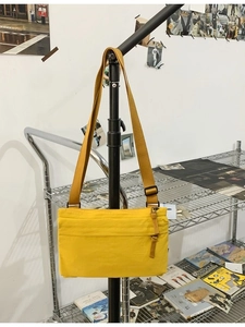 Minimalist bright yellow nylon shoulder bag with adjustable strap in casual scene
