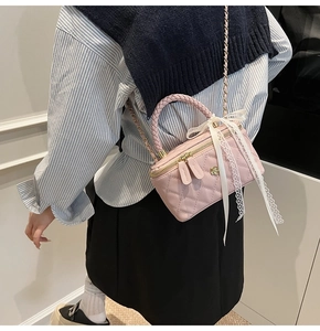 Detailed back view of pink quilted box bag with lace bow and chain strap on a model