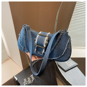 Detail of blue denim shoulder bag featuring silver metal buckle and frayed edge finish
