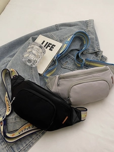 Black and grey nylon chest bags with letter-printed straps on denim background