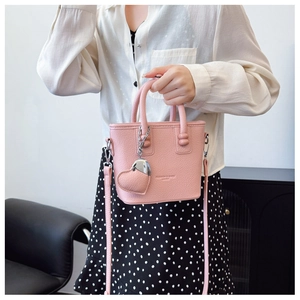 Detail der rosa Handtasche aus Leder mit Herzanhänger aus Metall und Kettenelement