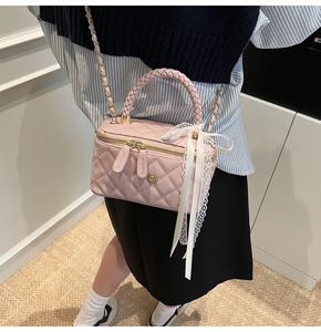 Detailed shot of pink quilted vanity bag with woven handle and lace bow detail