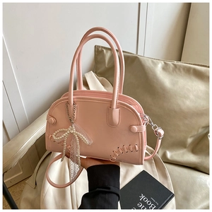 Détail du sac cabas rose avec pendentif nœud en perles et finitions en dentelle